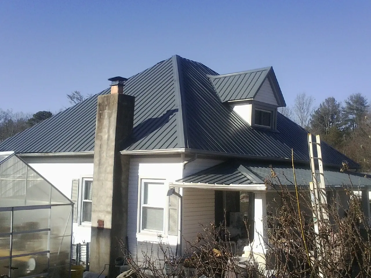 Dark blue standing seam metal roof on a white farmhouse with dormer — Slate & Tile Roof Repair by Roofing Brothers in Jacksontown