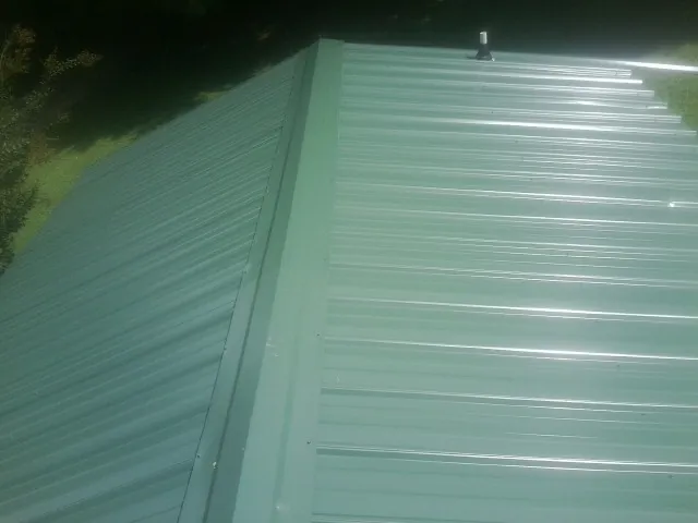 New green metal panels meeting at the ridge of a roof — Flat Roof Repair work by our crew in Jacksontown