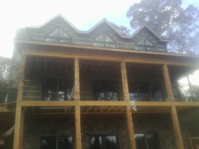 Dormers and porch framing on a large log home under construction — Roof Coating work by our crew in Jacksontown