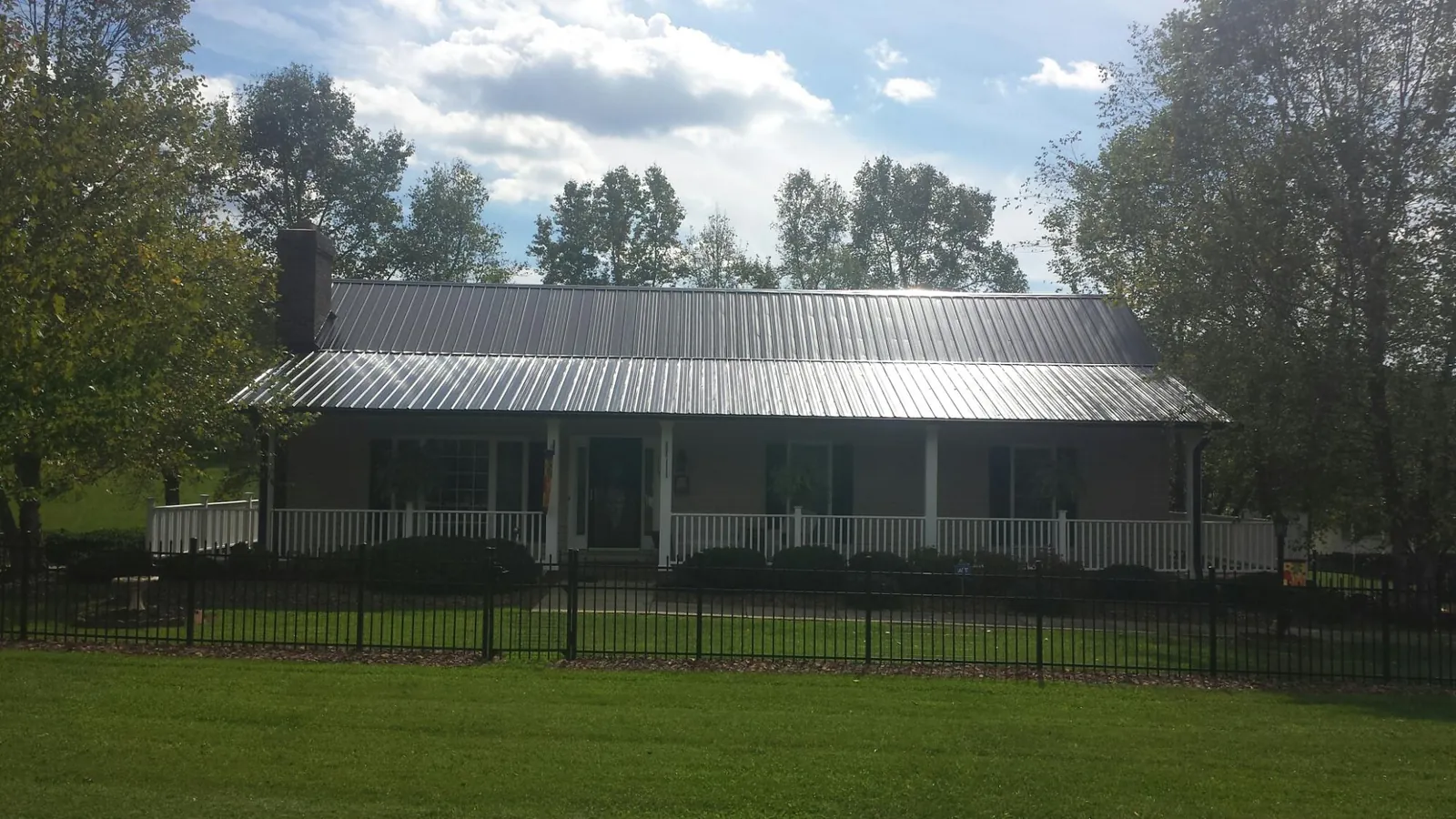Gray metal roof on a brick ranch with a full width front porch — Gutter Guard Installation work by our crew in Jacksontown