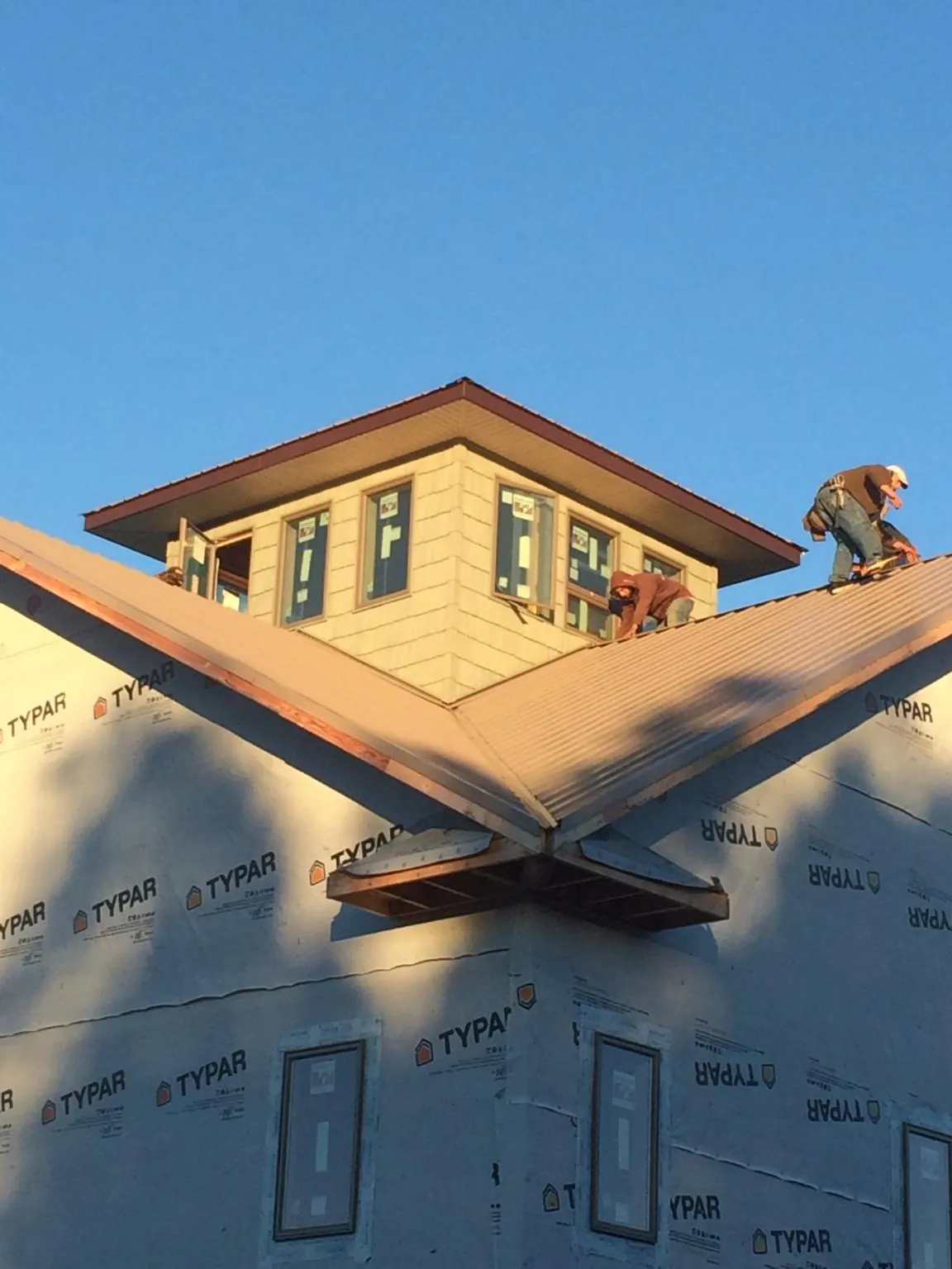Roofers working around a rooftop cupola on a new metal roof at sunset — Roof Waterproofing in Jacksontown by Roofing Brothers